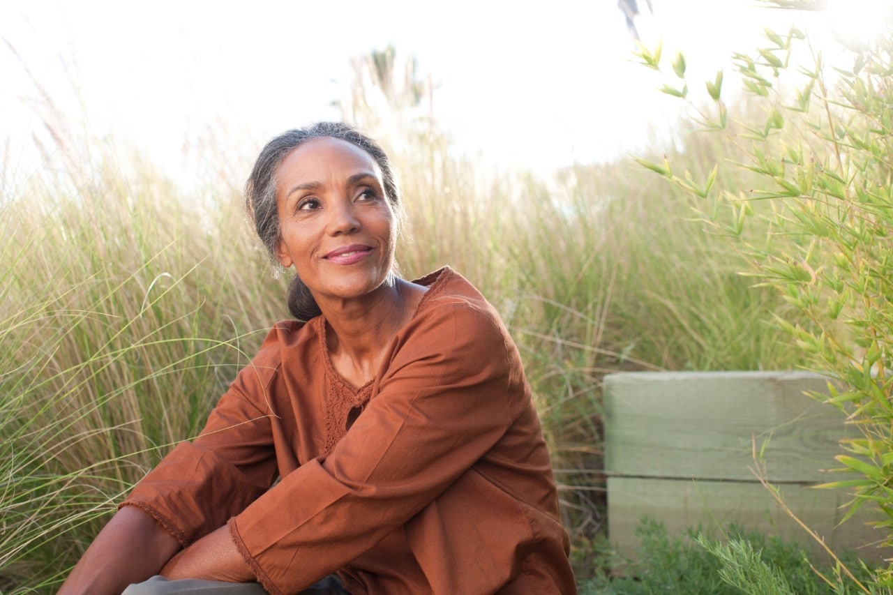 Serene woman sitting in sunny field